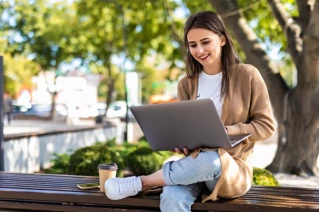 Kvinna sitter och arbetar på en laptop utomhus